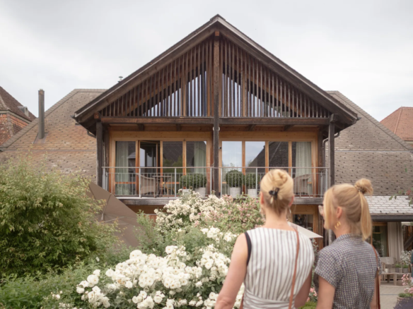 Brigitte und Sarita Walther von Immoment vor einem Holzhaus mit Garten